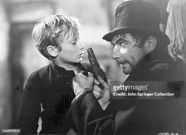 Bill Sikes, played by Robert Newton, threatens Oliver Twist who is played by John Howard Davies. From the 1948 film Oliver Twist.