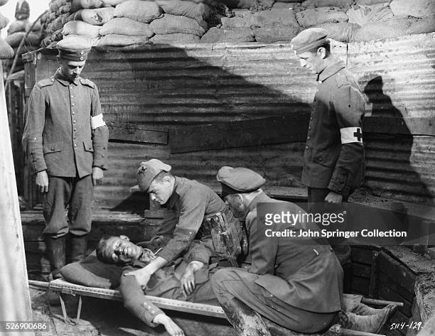 Officers help a wounded soldier onto a stretcher in a scene from All Quiet on the Western Front .