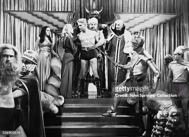 Princess Aura, Dale Arden, Flash Gordon, Dr. Zarkov and Emperor Ming standing in front of Mongo subjects.