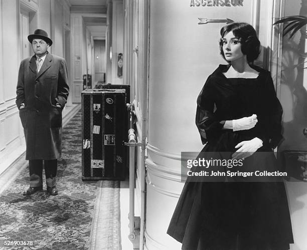 Ariane Chavasse hides around a hallway corner from Monsieur X (John McGiver in a scene from the 1957 comedic romance Love in the Afternoon.
