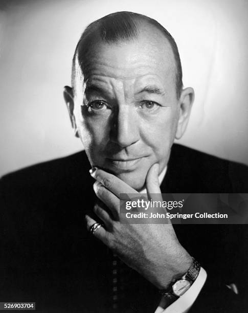 Head and shoulders portrait photo of British actor Noel Coward with his hand massaging his chin. Ca. 1950.