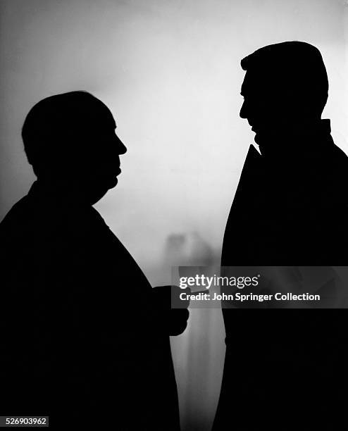Photo showing silhouettes of director Alfred Hitchcock pointing to actor Cary Grant, both from the waist-up. Ca. 1959. BPA2#990