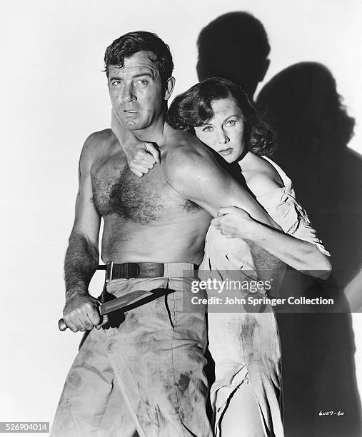 Steve Singleton protects Katherine Shelley , holding her behind him in a scene from the 1951 adventure Crosswinds.