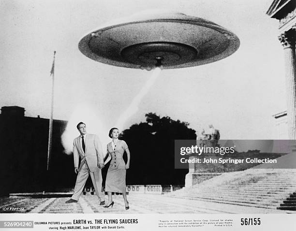 Poster of Hugh Marlowe and Joan Taylor walking below an alien spacecraft in the movie, Earth vs. The Flying Saucers.