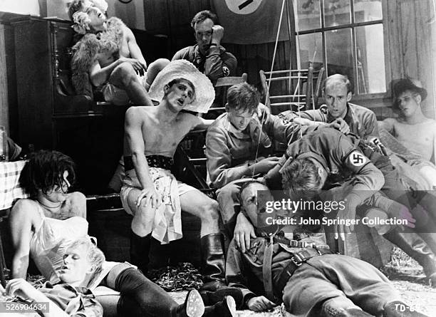 Fatigued members of the Third Reich sit with men dressed in drag in a scene from the 1969 film The Damned.