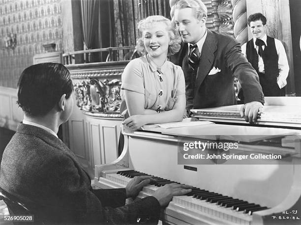 Actor Gene Raymond, actress Ann Sothern, and others listen to a pianist in the 1935 musical comedy Hooray for Love. Raymond plays the role of Doug...