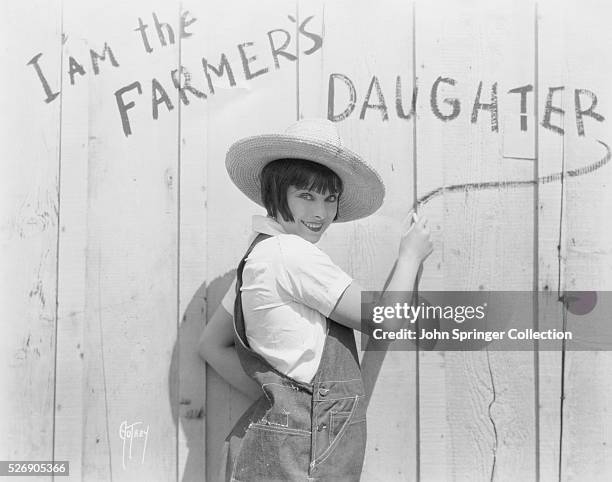 Marjorie Beebe writes "I am the farmer's daughter" on the side of a barn. The American actress plays the lead role of Margerine Hopkins in the 1928...