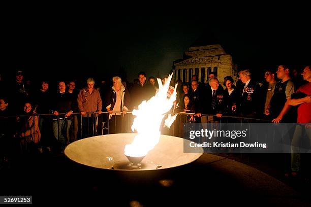 People gather around a fire lit during the memorial service held at the Shrine of Remembrance at a dawn service for Anzac Day April 25, 2005 in...