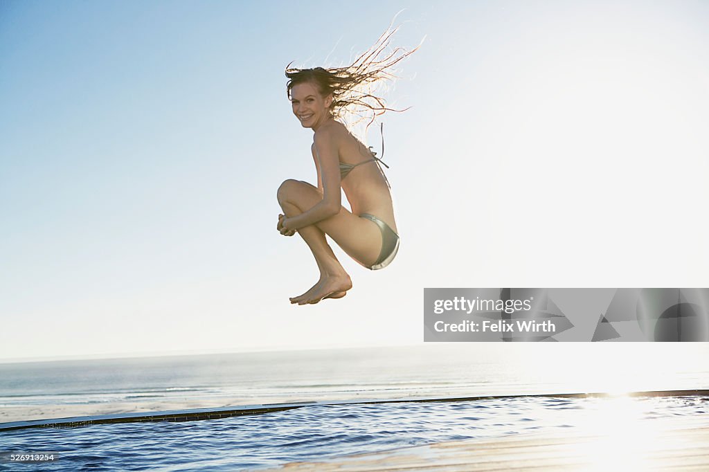 Woman doing cannonball into swimming pool