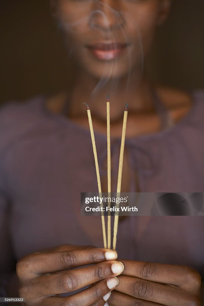 Woman holding three sticks of incense