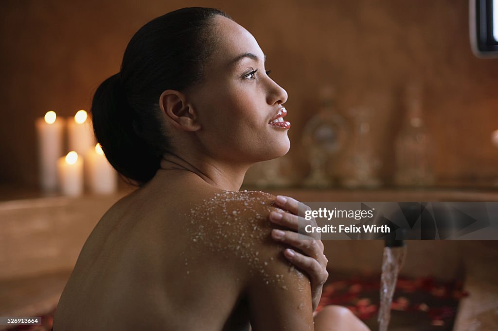 Woman using body scrub in bath