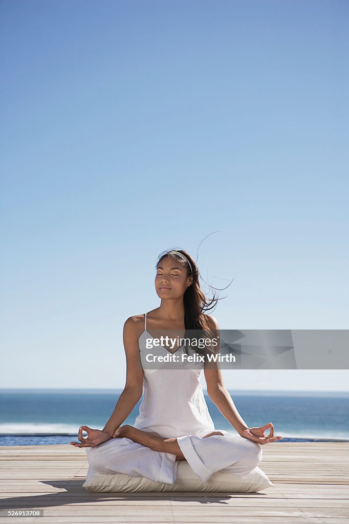 Woman meditating near ocean