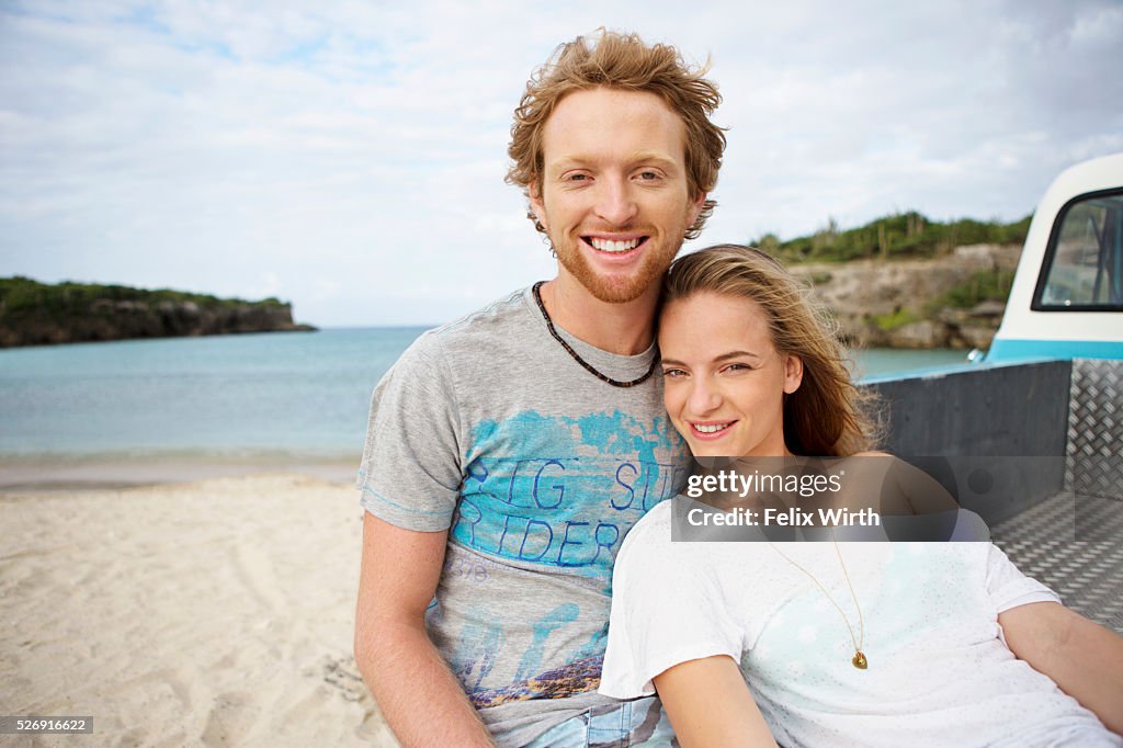 Couple sitting on tailgate of truck on beach