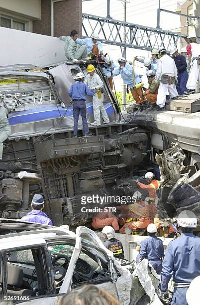 Rescue workers look for survivors from the wreckage of train carriages in Amagasaki, Hyogo prefecture, 25 April 2005. At least 16 people were killed...