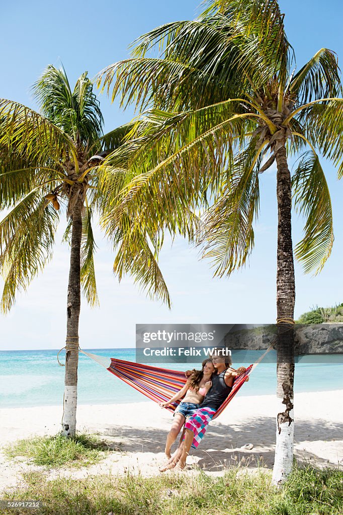 Young couple relaxing in hammock on beach