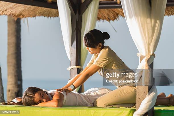 young woman having a massage under a gazebo - bali spa stock pictures, royalty-free photos & images