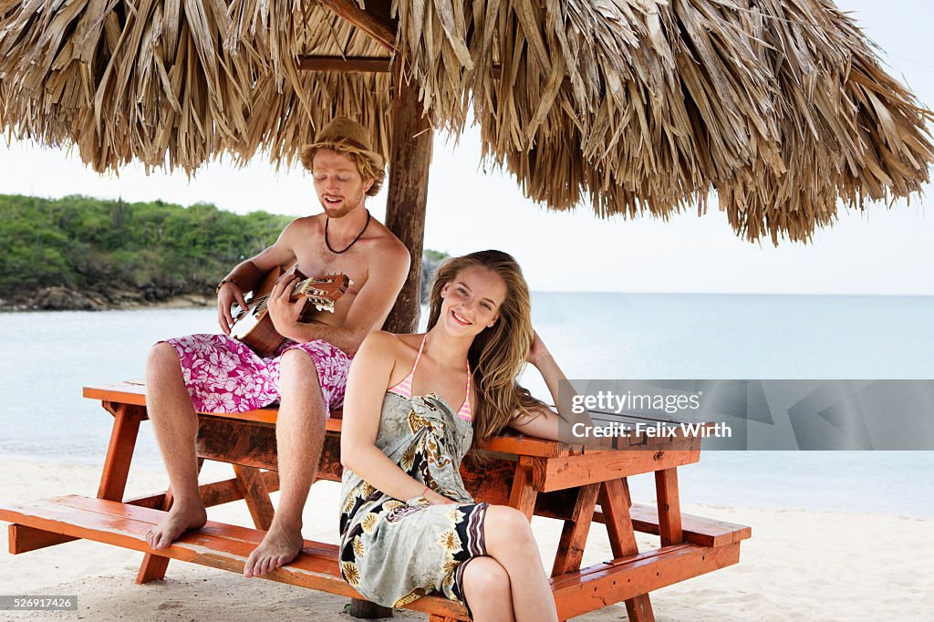 Couple relaxing on beach under sunshade