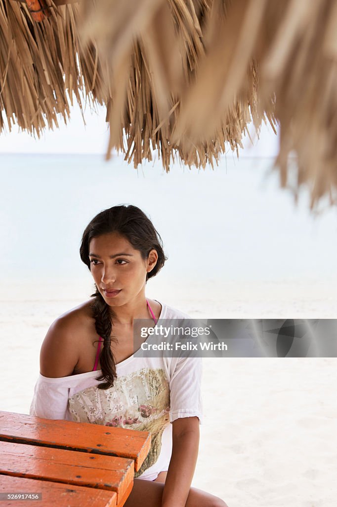 Woman relaxing on beach under sunshade