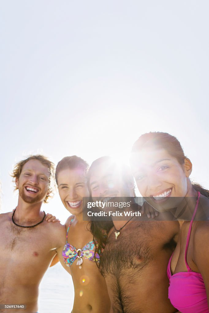 Group of friends posing together on sandy beach