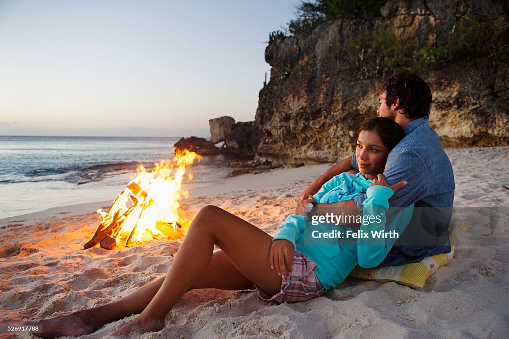 Couple relaxing on beach at campfire