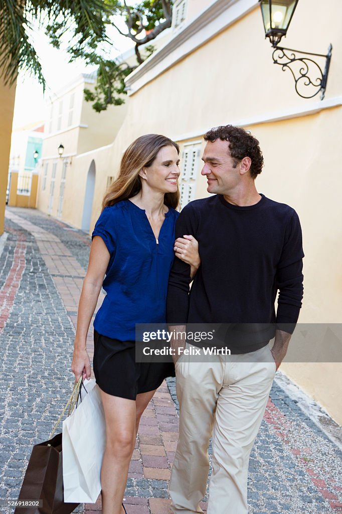 Couple walking arm in arm along cobblestone street