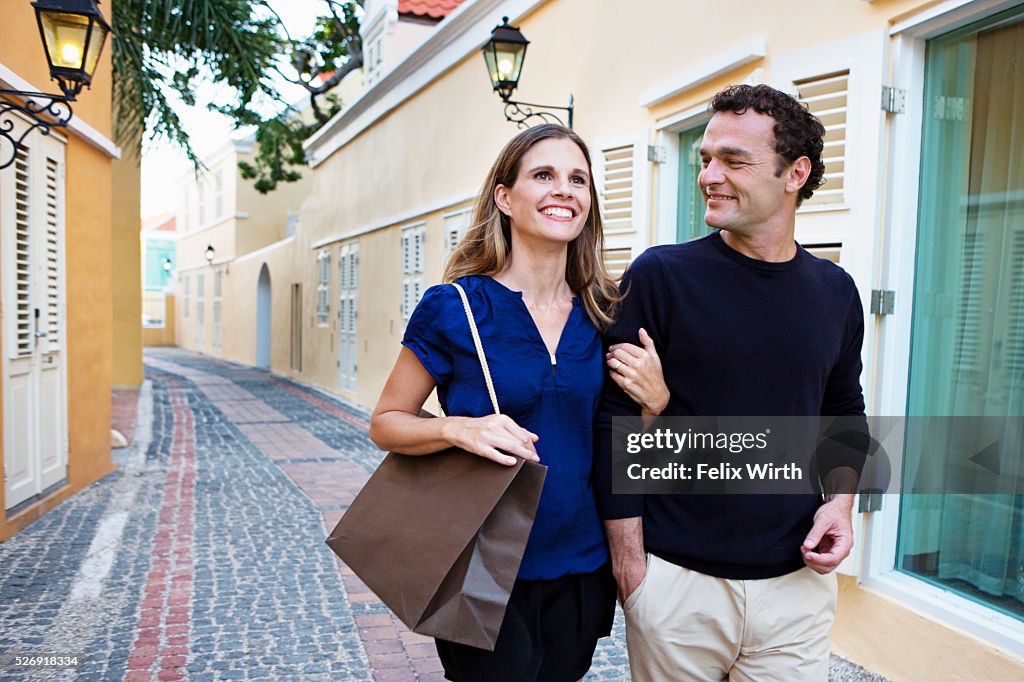 Couple walking arm in arm along cobblestone street