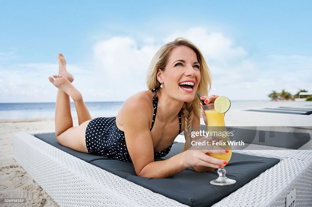 Portrait of woman having drink on deck chair on beach