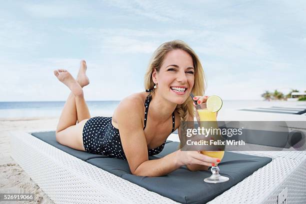 portrait of woman having drink on deck chair on beach - beach deck chairs stock-fotos und bilder