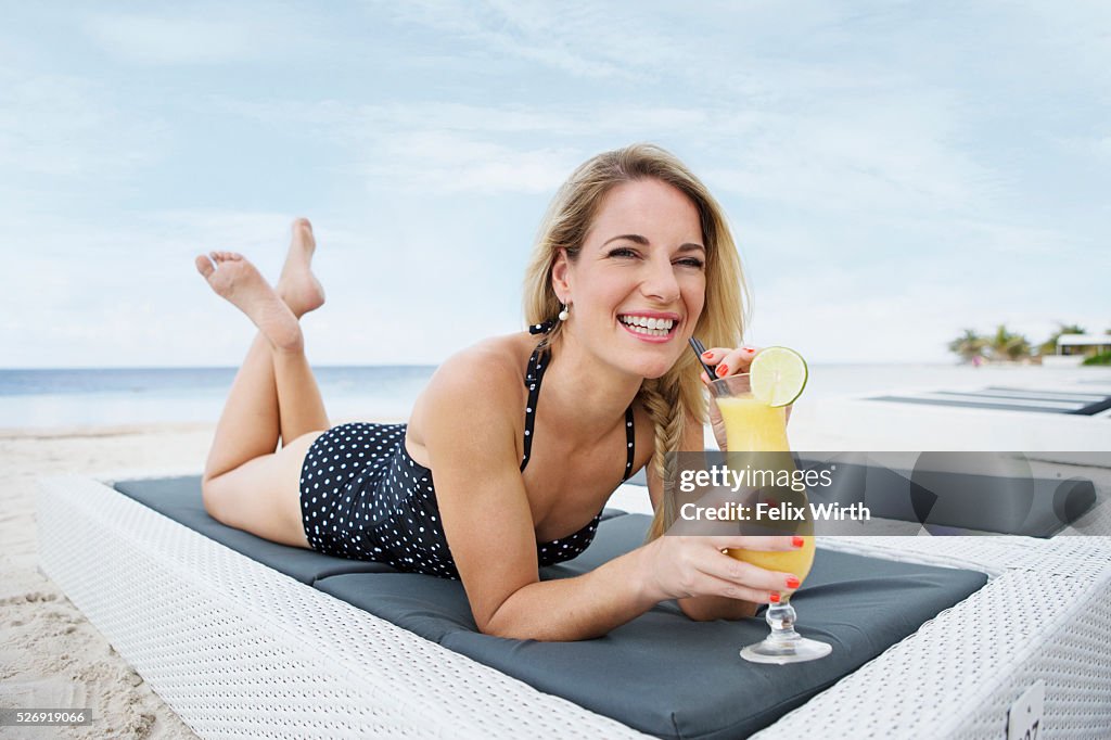 Portrait of woman having drink on deck chair on beach
