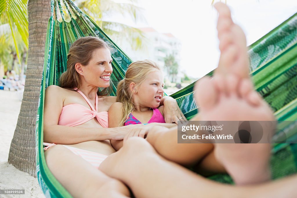 Mother and children (10-12) relaxing in hammock on beach