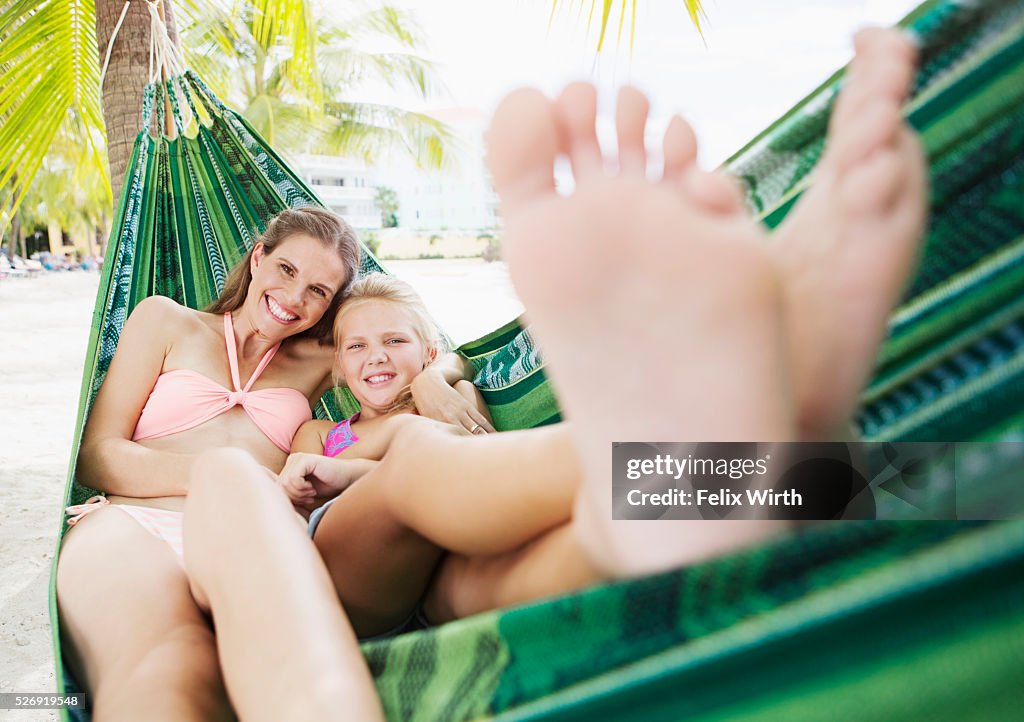 Mother and daughter (10-12) relaxing in hammock on beach