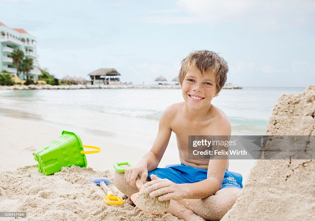Portrait of boy (10-12) playing on beach in sand