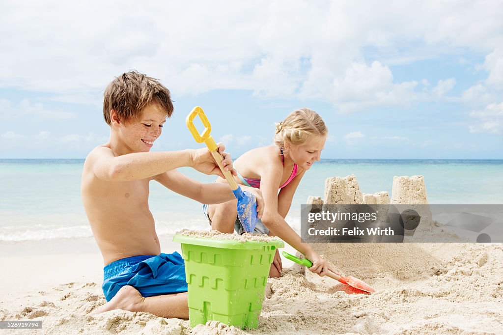 Children (10-12) playing on beach in sand