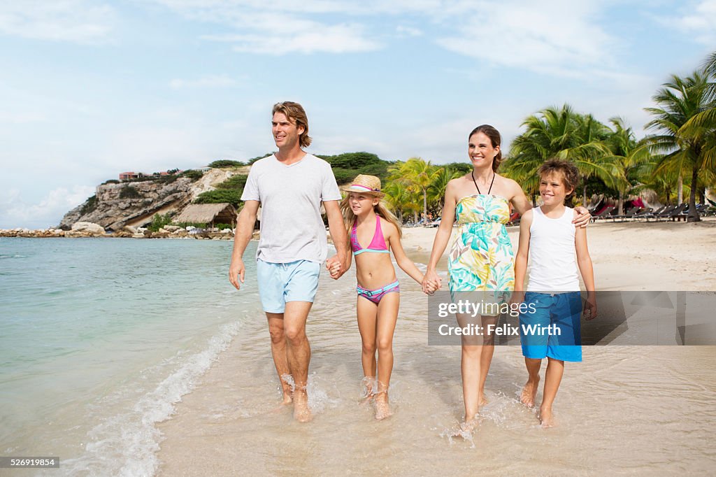 Happy family with children (10-12) walking along beach