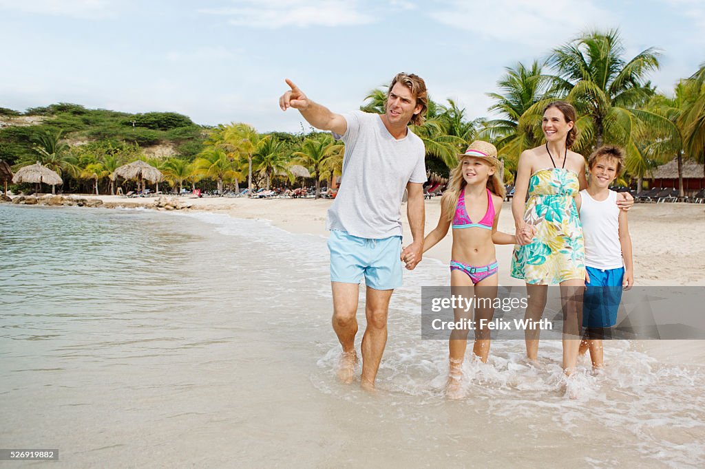 Happy family with children (10-12) walking along beach