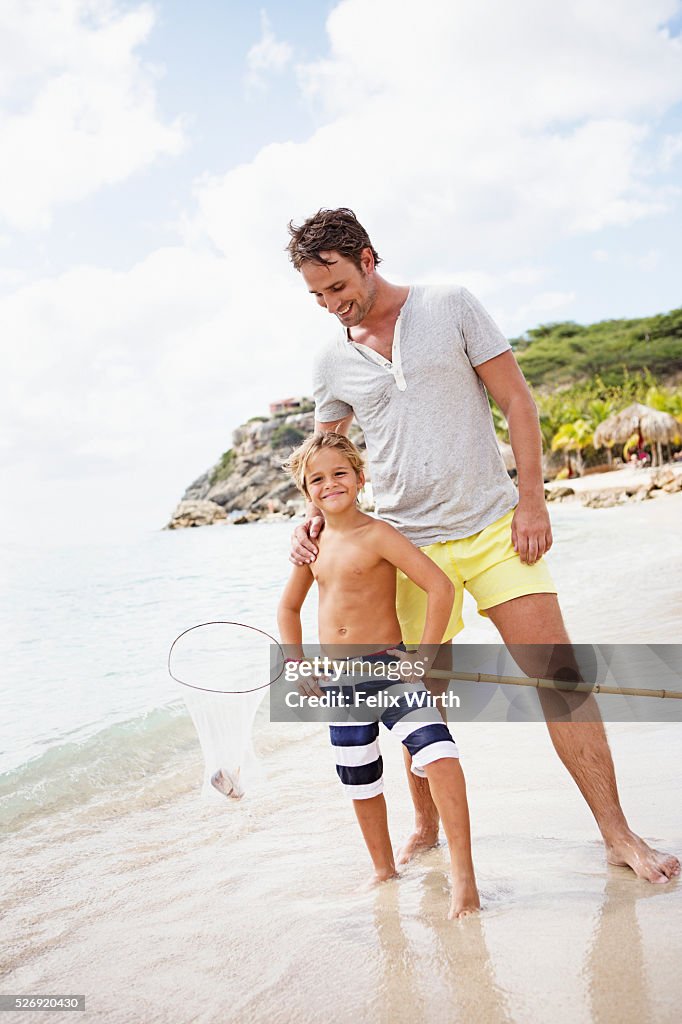 Father with son (8-9) holding fishing net