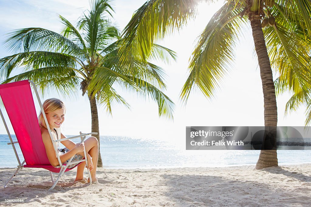 Girl (10-11) relaxing on beach lounger