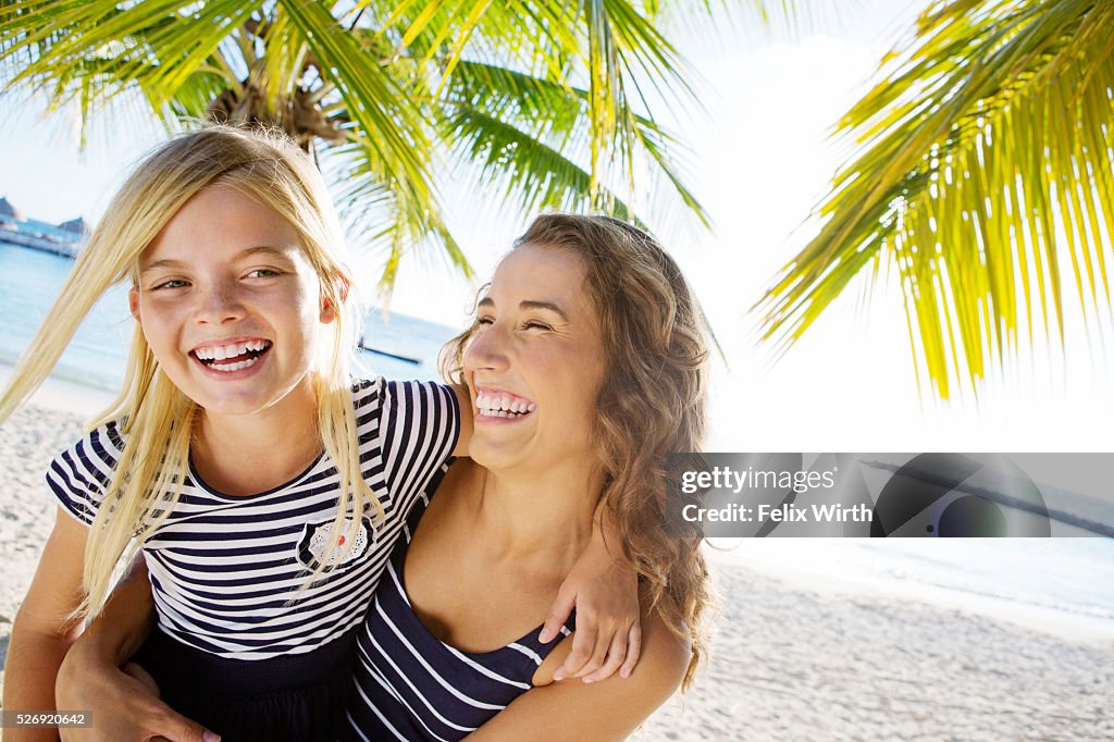 Mother with daughter (10-11) laughing on beach