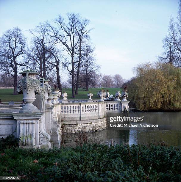 Stone urns punctuate an ornamental balustrade which encloses a water garden in Kensington Gardens, London, England.
