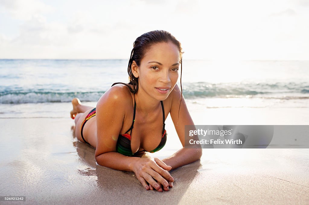 Young woman lying on sand on tropical beach