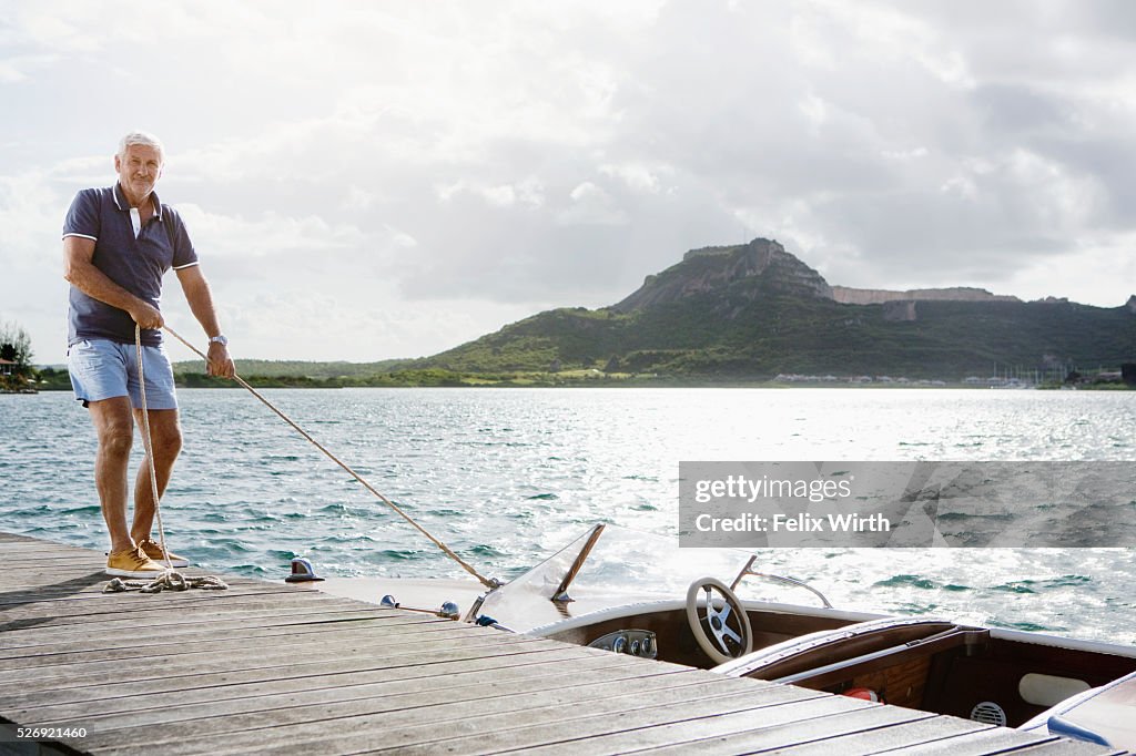 Senior man standing on jetty with moored motorboat