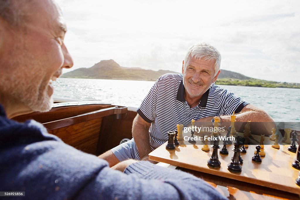 Two senior friends playing chess in motorboat