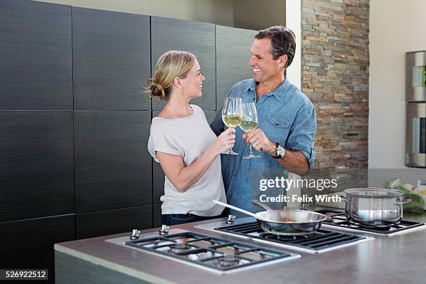 middle-aged couple cooking together and drinking wine - couple having dinner stock pictures, royalty-free photos & images