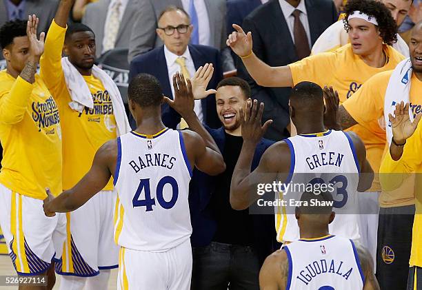 Stephen Curry of the Golden State Warriors congratulates Harrison Barnes and Draymond Green during a time out of their game against the Portland...