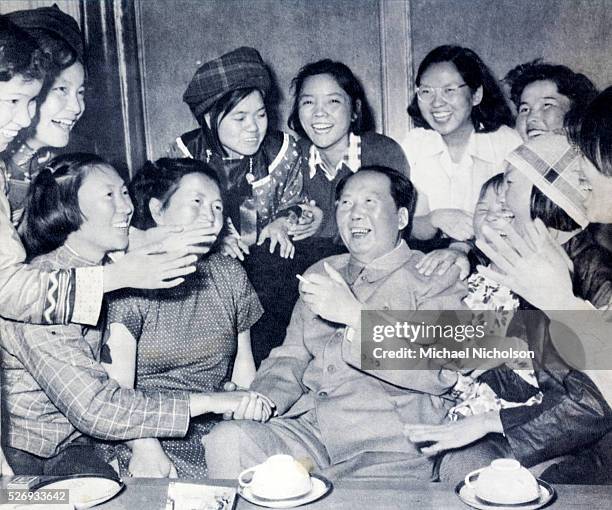 Mao Zedong . Photograph from 1957 showing him laughing and surrounded by a group of deighted women, some in modern and some in ethnic dress. The...