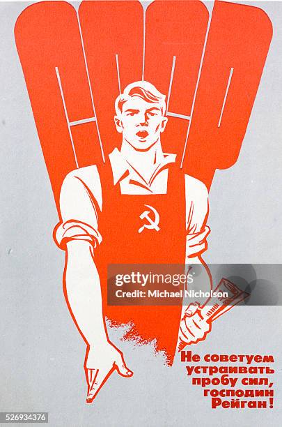 He ist standing in front of a giant USSR motif.At the bottom is a slogan. Communist propaganda poster.