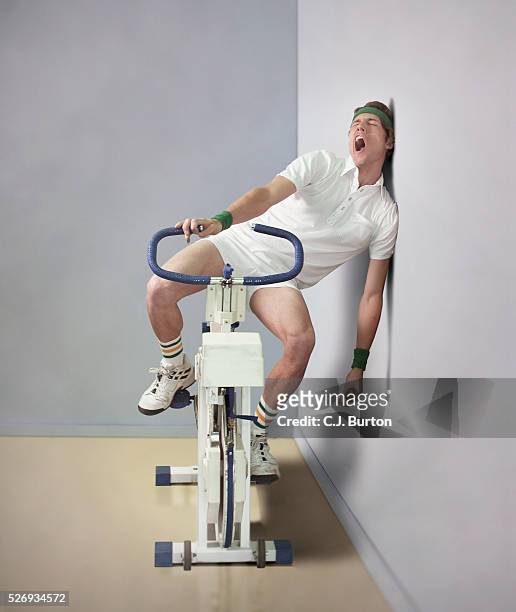 man yawning while sitting on exercise bicycle - fatigue full body stock-fotos und bilder