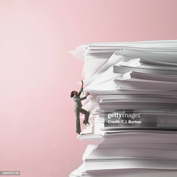 businesswoman climbing stack of documents - workload stock-fotos und bilder