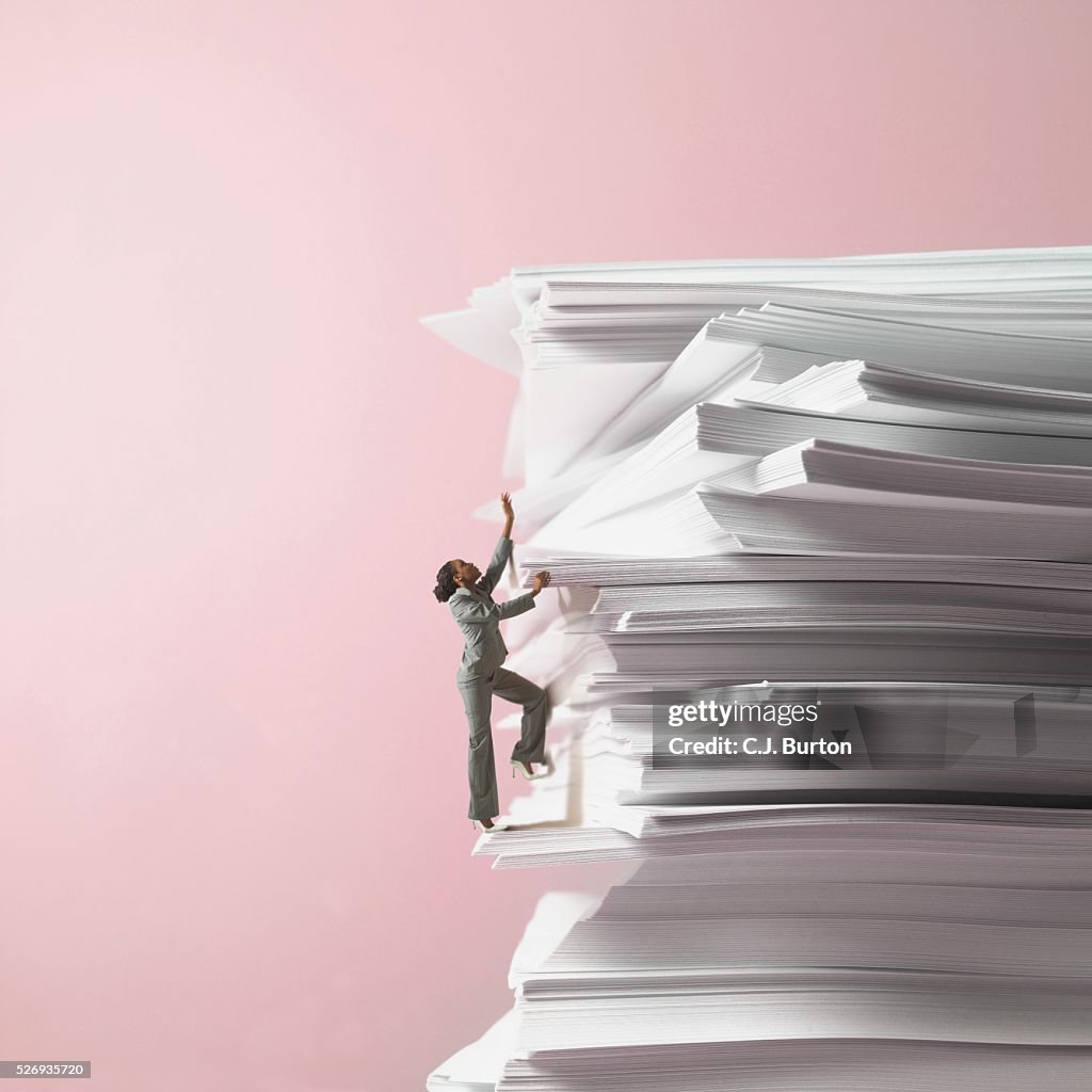Businesswoman climbing stack of documents