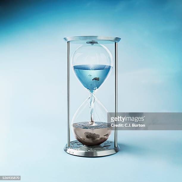 hourglass with clean ocean water in the top and dirty polluted water in bottom - sablier photos et images de collection